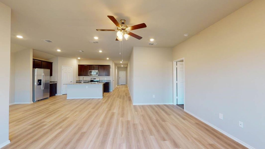 Kitchen featuring open floor plan, stainless steel appliances, dark brown cabinetry, a kitchen island with sink, and a ceiling fan