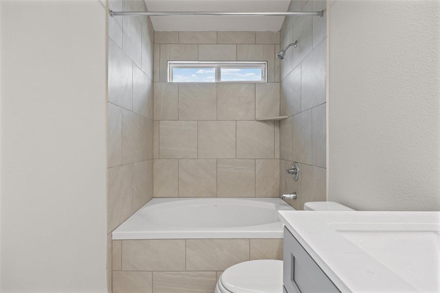 Tiled walls surround a deep soaking tub featuring a high transom window. Tiled walls surround a deep soaking tub featuring a high transom window.