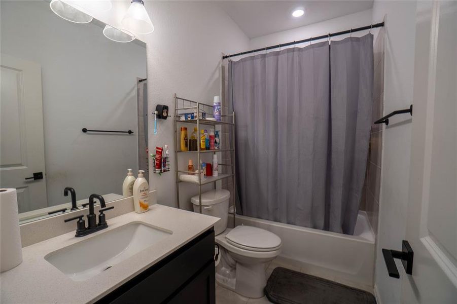 Bathroom featuring a single vanity with stone-finish countertop, undermount sink, and matte black faucet