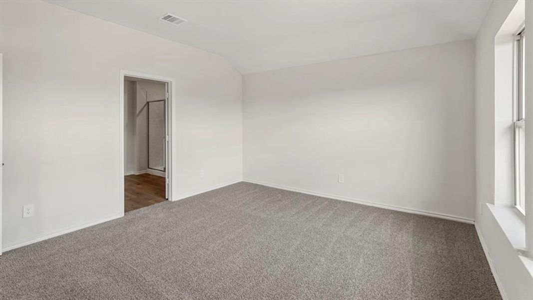 Spacious room featuring neutral carpeting, white walls, a large window, and a door frame