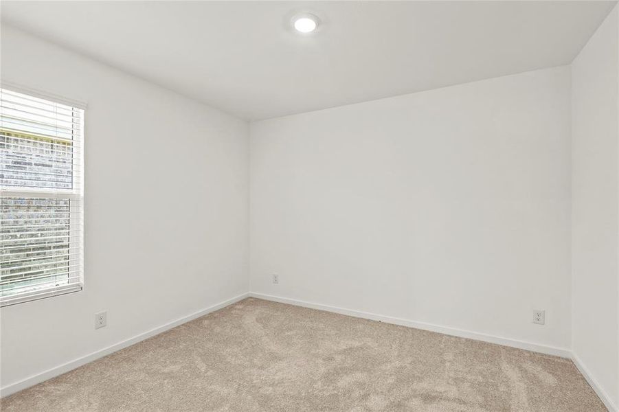 Neutral tone carpeted room with white walls and a single window featuring horizontal blinds