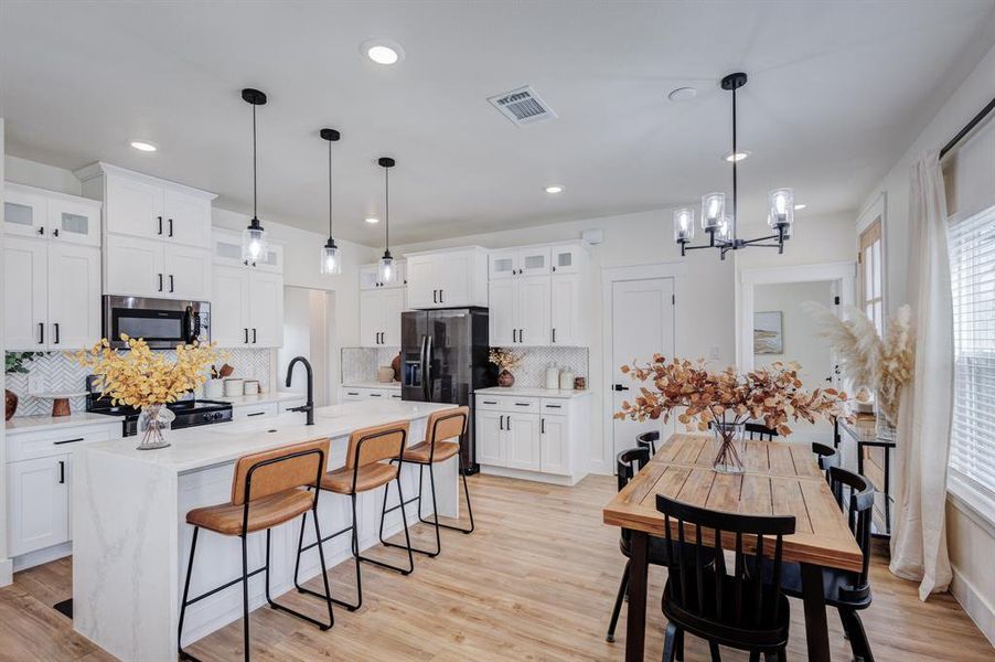 Kitchen with pendant lighting, stainless steel appliances, a center island with sink, and white cabinets Kitchen with pendant lighting, stainless steel appliances, a center island with sink, and white cabinets