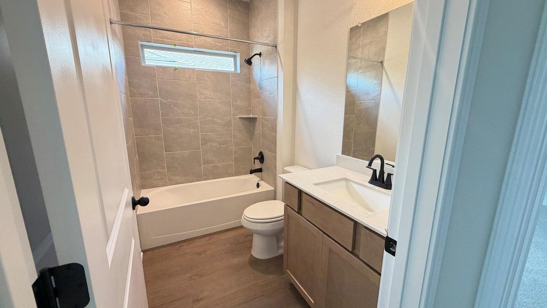 A well-appointed bathroom with a spacious vanity, sleek tiling, and a convenient window above the tub. A well-appointed bathroom with a spacious vanity, sleek tiling, and a convenient window above the tub.