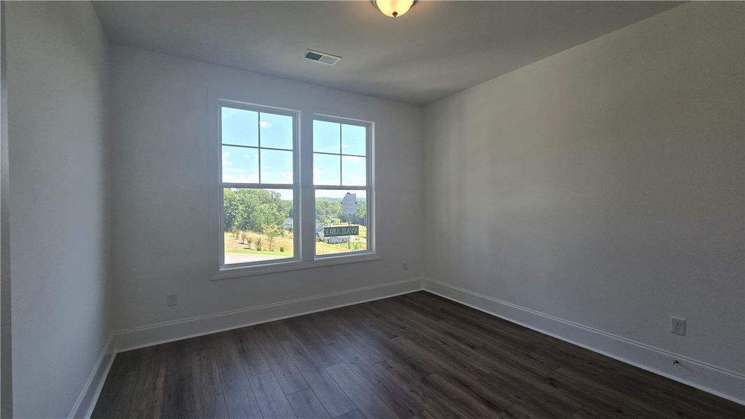 A well-lit room features dark wood flooring, offer