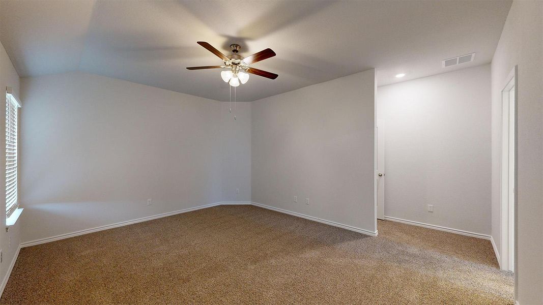 Empty room featuring ceiling fan, light colored carpet, and lofted ceiling
