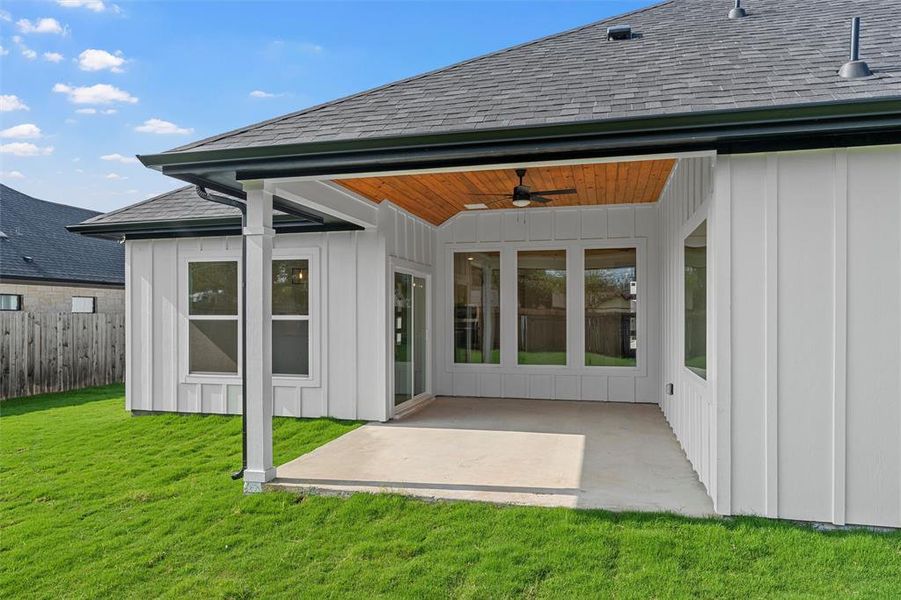 Rear view of house featuring roof with shingles, ceiling fan, board and batten siding, and a patio Rear view of house featuring roof with shingles, ceiling fan, board and batten siding, and a patio