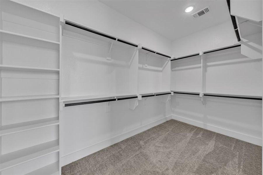 Walk-in closet featuring built-in shelving, multiple hanging rods, white walls, and a recessed ceiling light
