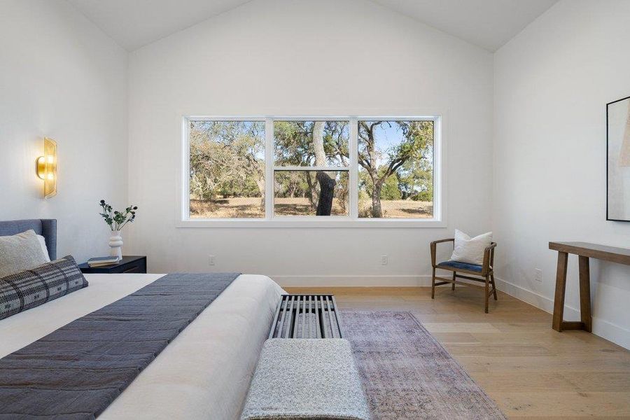 Bedroom with light wood-style flooring, multiple windows, and vaulted ceiling