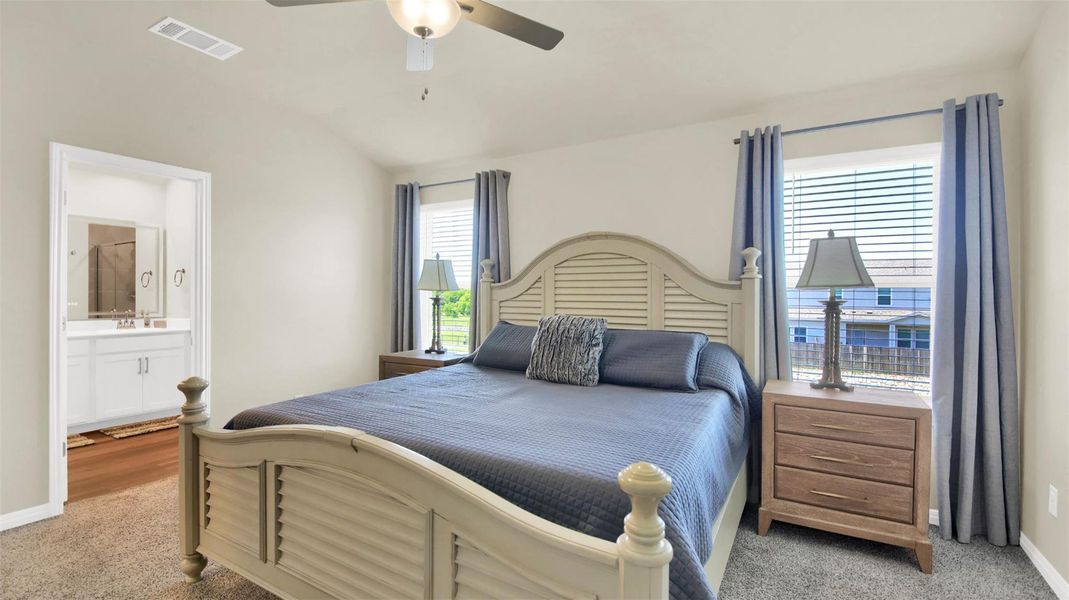 Primary bedroom with vaulted ceiling and carpet flooring
