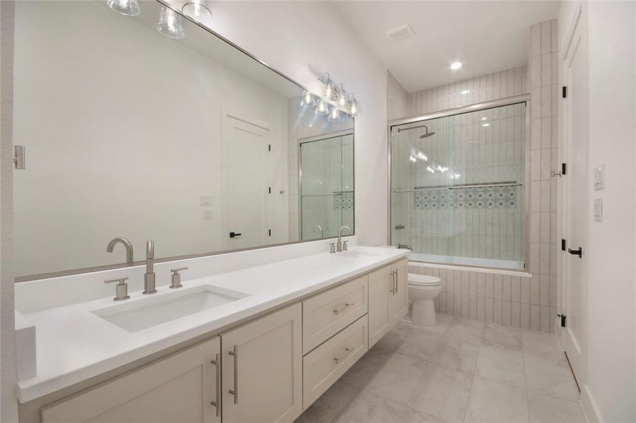 Bathroom with double vanity, tiled shower / bath, and recessed lighting