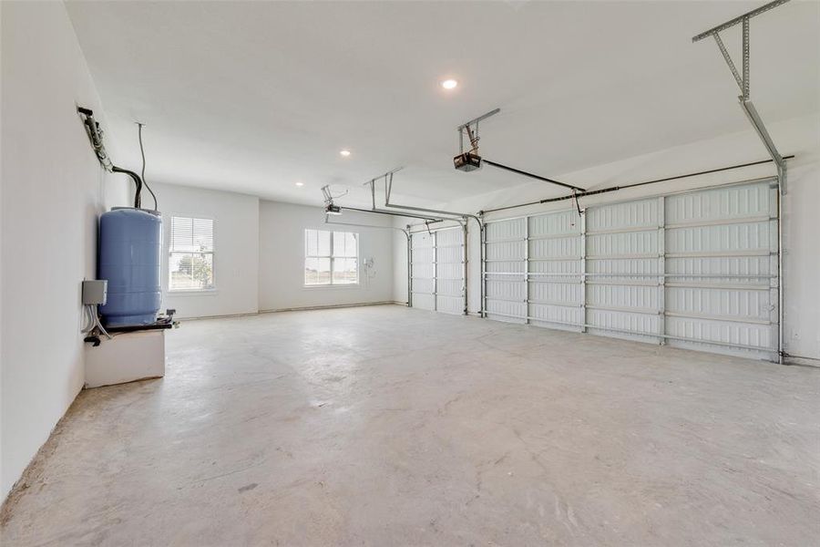Spacious garage featuring a concrete floor, two garage doors with openers, multiple windows, and recessed lighting