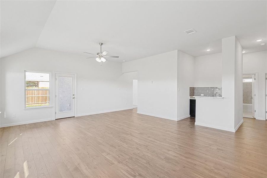 Unfurnished living room with light hardwood / wood-style floors, ceiling fan, and lofted ceiling