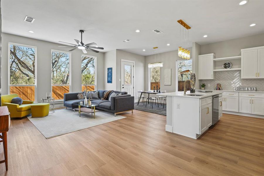 Kitchen featuring visible vents, white cabinets, open floor plan, light countertops, and a center island with sink