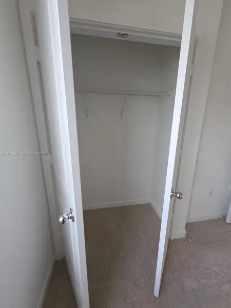 Interior closet featuring two swinging doors, chrome hardware, and integrated wire shelving