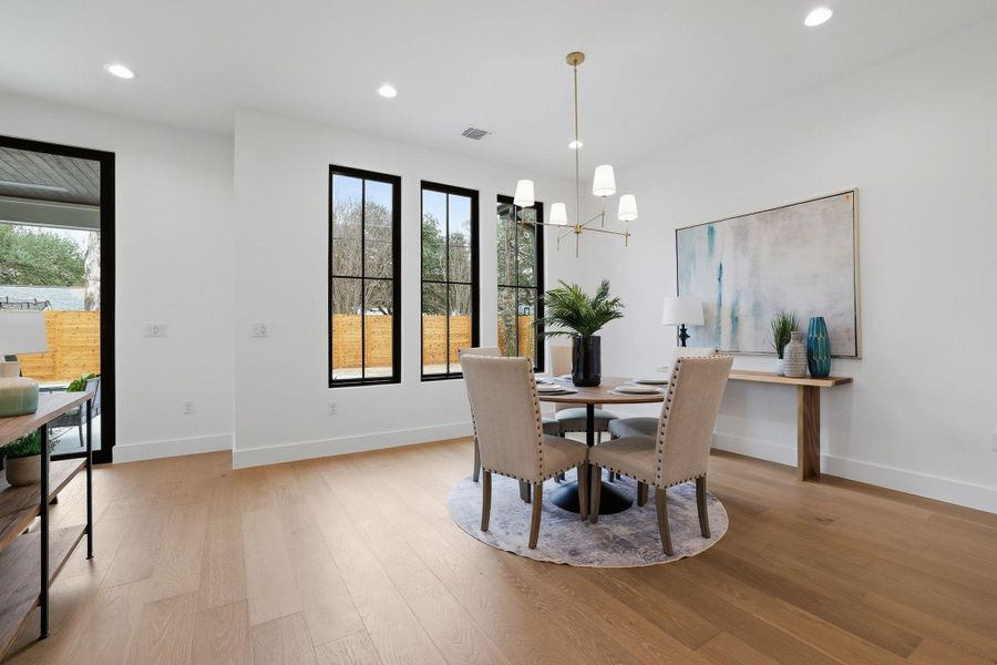 Open-concept dining area featuring wood-finish flooring, recessed lighting, and a modern chandelier