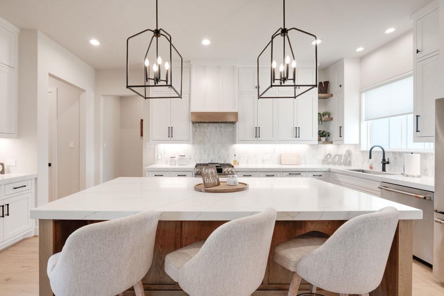 Kitchen with open shelves, hanging lights, stainless steel appliances, light stone countertops, and two tone cabinets
