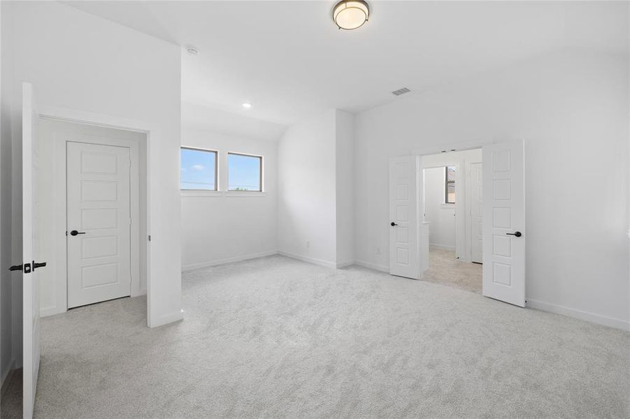 Carpeted room featuring white walls, a flush-mount ceiling light fixture, and multiple windows