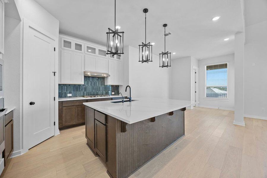 Kitchen featuring a chandelier, stainless steel gas stovetop, light wood finished floors, light countertops, and recessed lighting Kitchen featuring a chandelier, stainless steel gas stovetop, light wood finished floors, light countertops, and recessed lighting