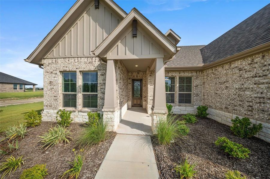 Doorway to property with board and batten siding, brick siding, and roof with shingles Doorway to property with board and batten siding, brick siding, and roof with shingles