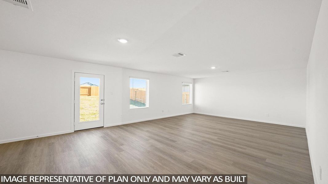 A spacious, naturally illuminated room featuring warm wood flooring and convenient exterior access.