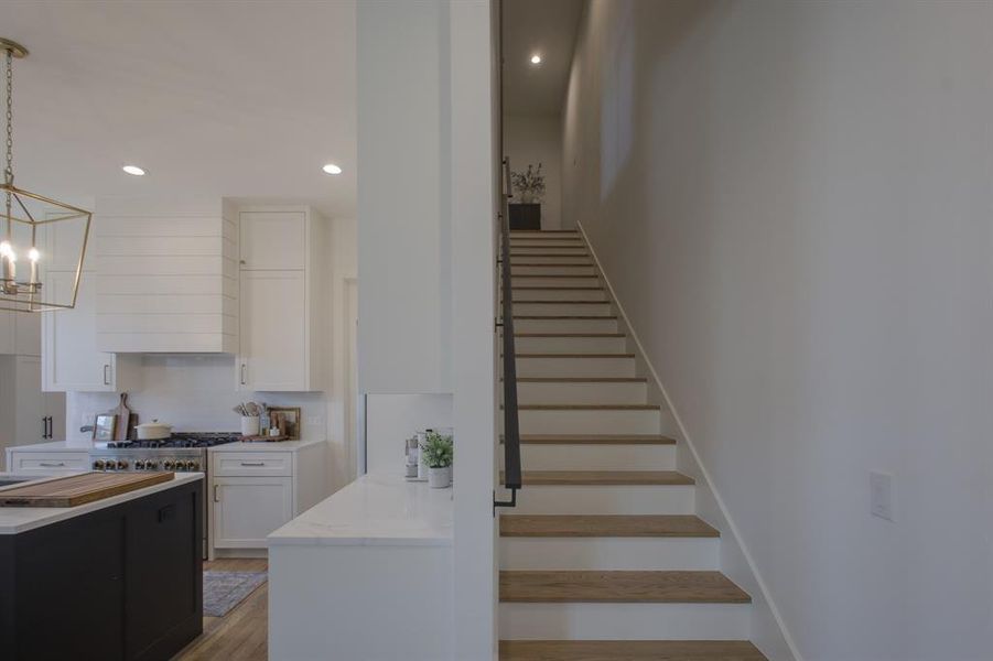 Stairway with hardwood / wood-style floors and a notable chandelier