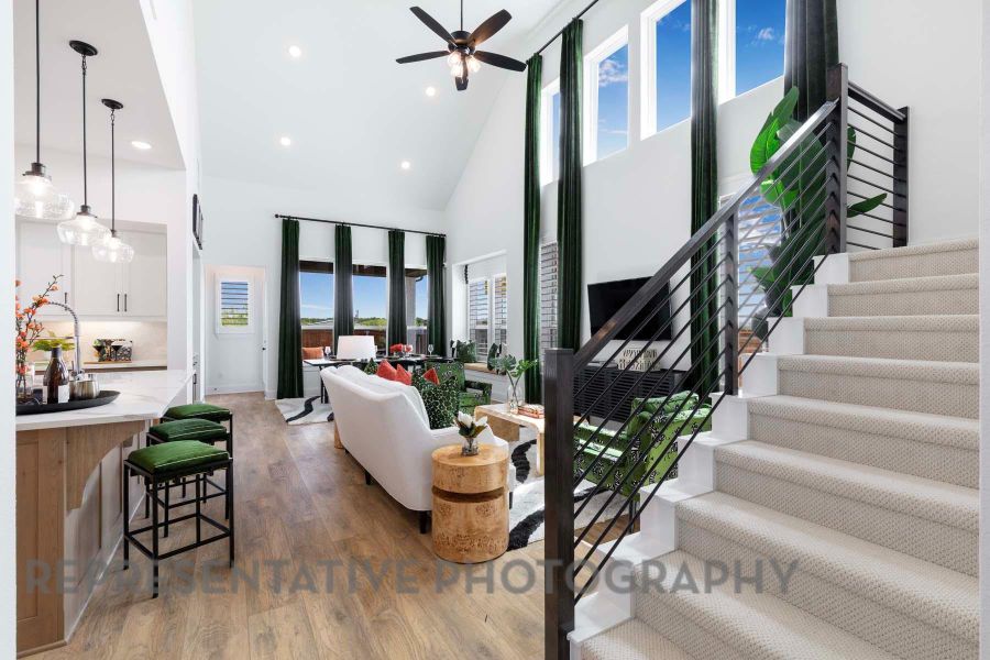 Living room featuring light wood-type flooring, high vaulted ceiling, a ceiling fan, and plenty of natural light Living room featuring light wood-type flooring, high vaulted ceiling, a ceiling fan, and plenty of natural light