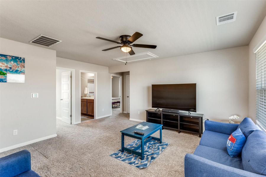Living area featuring attic access, ceiling fan, and light colored carpet
