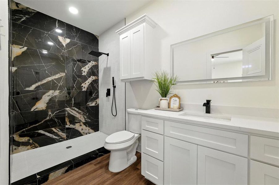 Full bath featuring vanity, a marble finish shower, wood finished floors, and recessed lighting