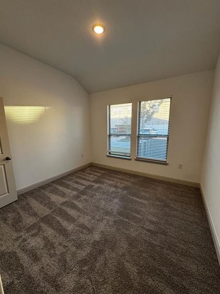 Carpeted spare room featuring lofted ceiling