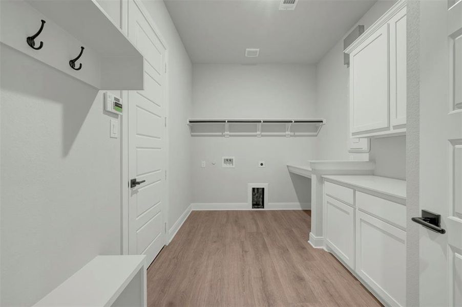 Laundry area featuring light wood-style flooring, electric dryer hookup, hookup for a washing machine, and cabinet space