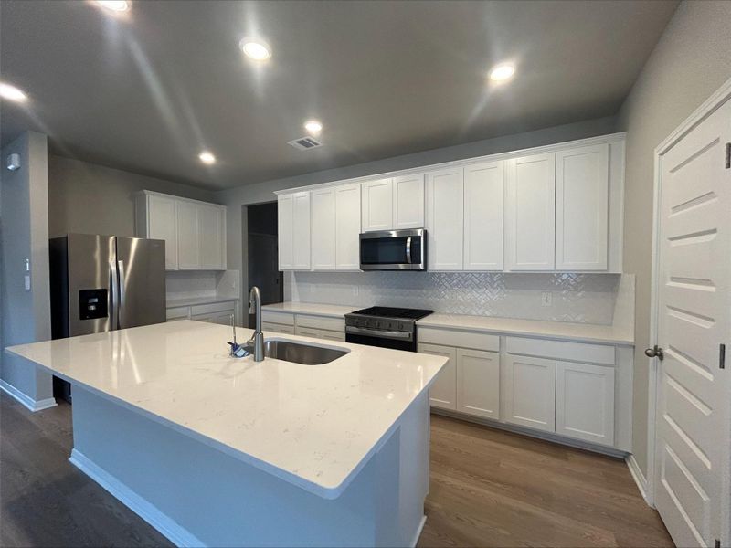Kitchen featuring dark wood-type flooring, stainless steel appliances, tasteful backsplash, white cabinets, and recessed lighting Kitchen featuring dark wood-type flooring, stainless steel appliances, tasteful backsplash, white cabinets, and recessed lighting