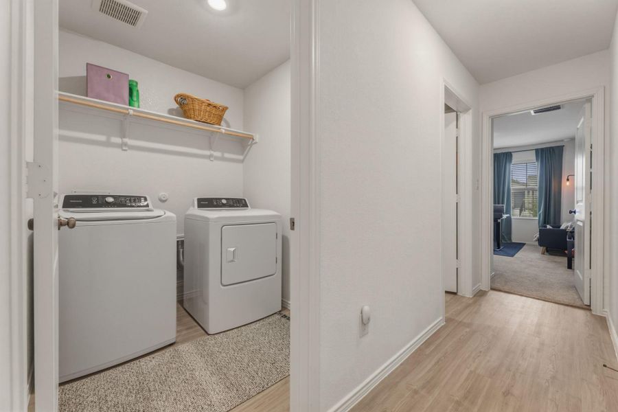 Dedicated laundry area featuring a washer and dryer, with shelving for storage, and light-toned flooring