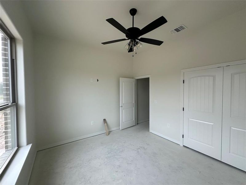 Unfurnished bedroom with unfinished concrete floors, ceiling fan, and a closet
