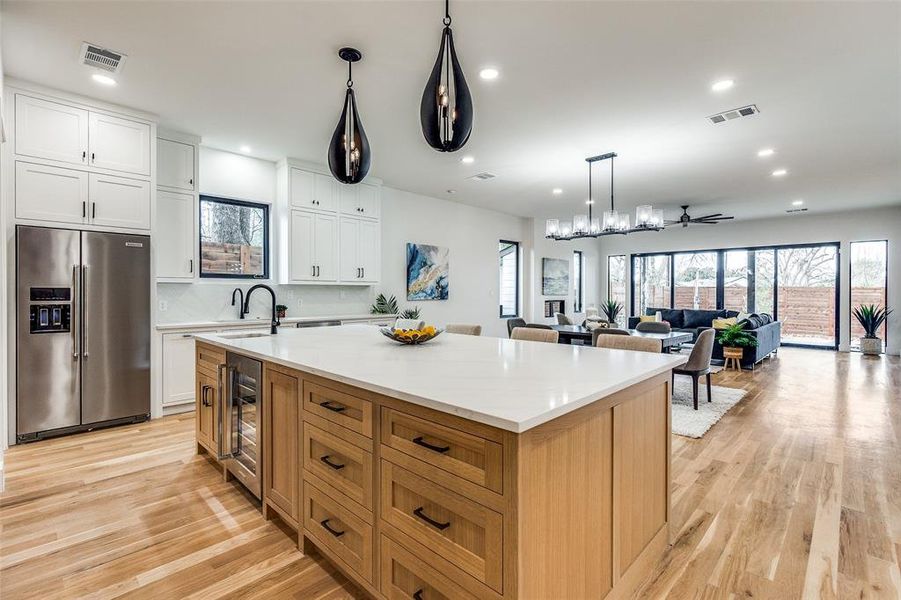 Kitchen featuring stainless steel fridge, ceiling fan, white cabinets, wine cooler, and a large island