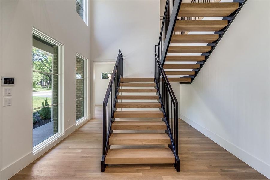 Stairs featuring wood finished floors and a high ceiling Stairs featuring wood finished floors and a high ceiling