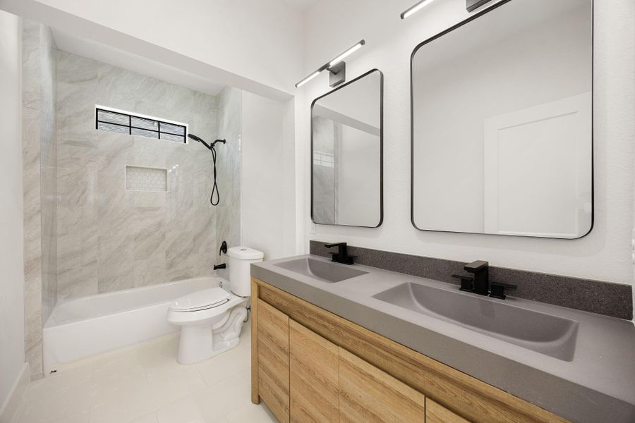 A beautiful appointed bathroom featuring a double vanity with two side-by-side mirrors, LED lighting, and a convenient tub and shower combination.