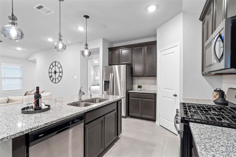 A modern stainless steel French-door refrigerator provides ample storage, complemented by a dedicated secondary counter space with matching granite countertops, perfect for a coffee station or additional prep area.