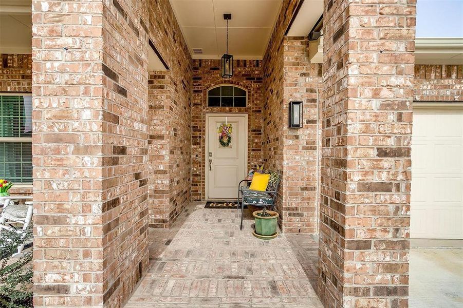 Property entrance featuring a garage, brick siding, and visible vents