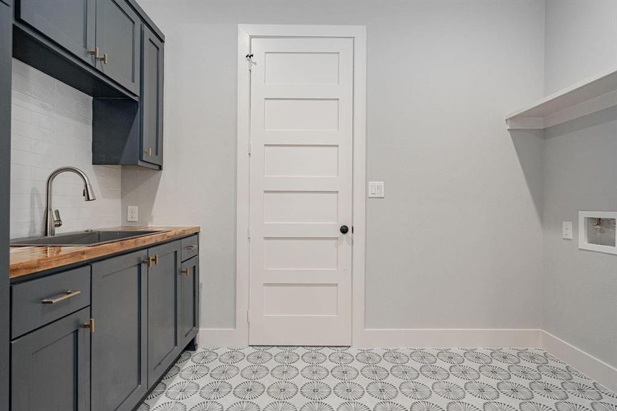 Example of builders Laundry area with cabinets, sink, and hookup for a washing machine