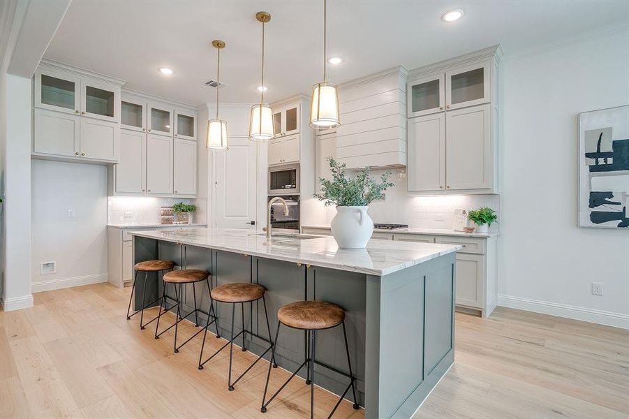 Kitchen with custom cabinets to the ceiling, leathered Quartzite counters, tile backsplash, decorative lighting, ample storage, soft close doors and drawers, and gas cooktop. Kitchen with custom cabinets to the ceiling, leathered Quartzite counters, tile backsplash, decorative lighting, ample storage, soft close doors and drawers, and gas cooktop.