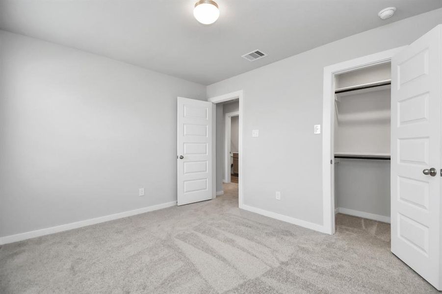 Secondary bedroom features plush carpeting, large windows that let in plenty of natural light, bright paint, and spacious closets. Sample photo of completed home with similar floor plan. Actual colors and selections may vary.