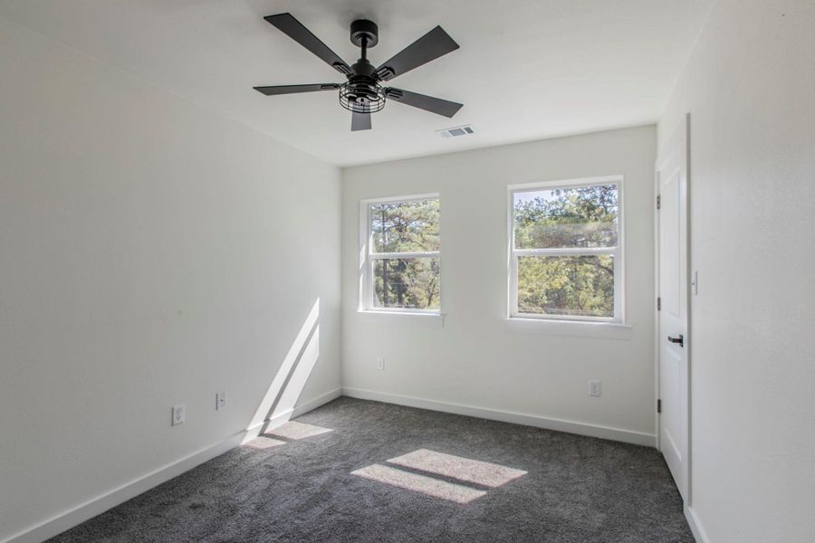 Empty room with dark colored carpet and ceiling fan