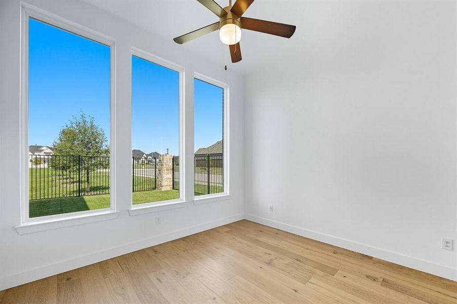 Spare room with light wood-style flooring, a residential view, and a ceiling fan Spare room with light wood-style flooring, a residential view, and a ceiling fan