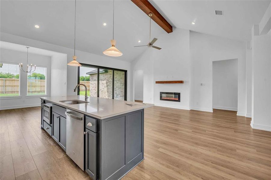Kitchen featuring beam ceiling, a sink, light wood finished floors, stainless steel dishwasher, and gray cabinetry Kitchen featuring beam ceiling, a sink, light wood finished floors, stainless steel dishwasher, and gray cabinetry