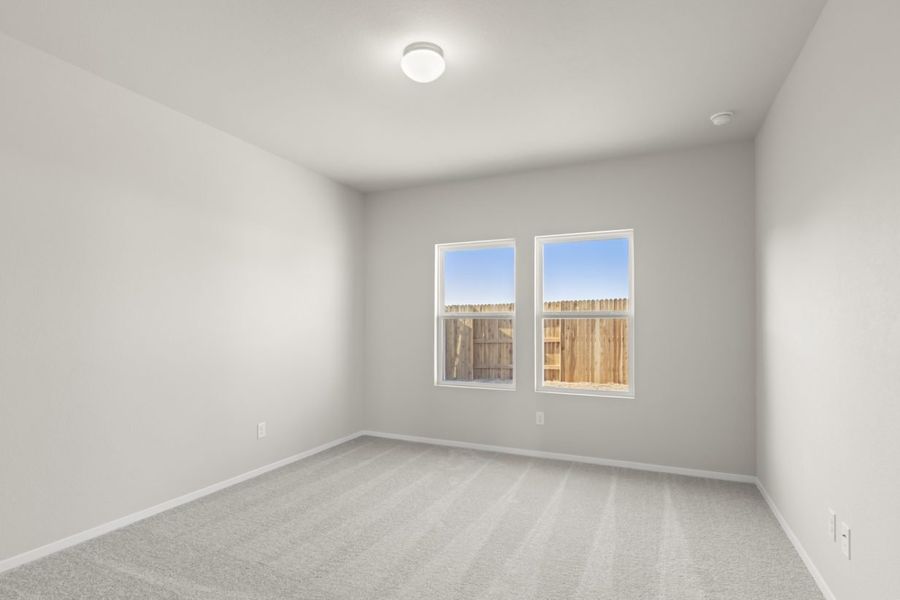 Image of a primary bedroom with light grey walls, tan carpeting, two windows, and white trim Image of a primary bedroom with light grey walls, tan carpeting, two windows, and white trim