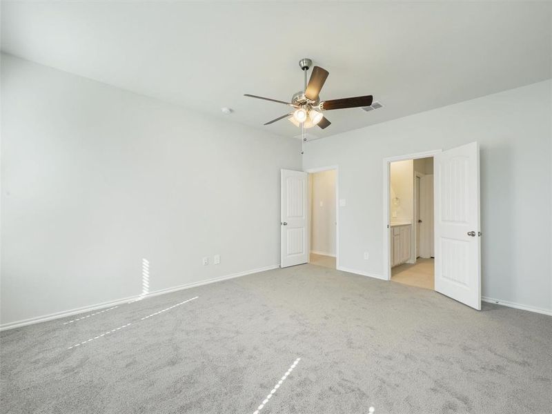 Unfurnished bedroom featuring light colored carpet, visible vents, ensuite bathroom, and baseboards Unfurnished bedroom featuring light colored carpet, visible vents, ensuite bathroom, and baseboards