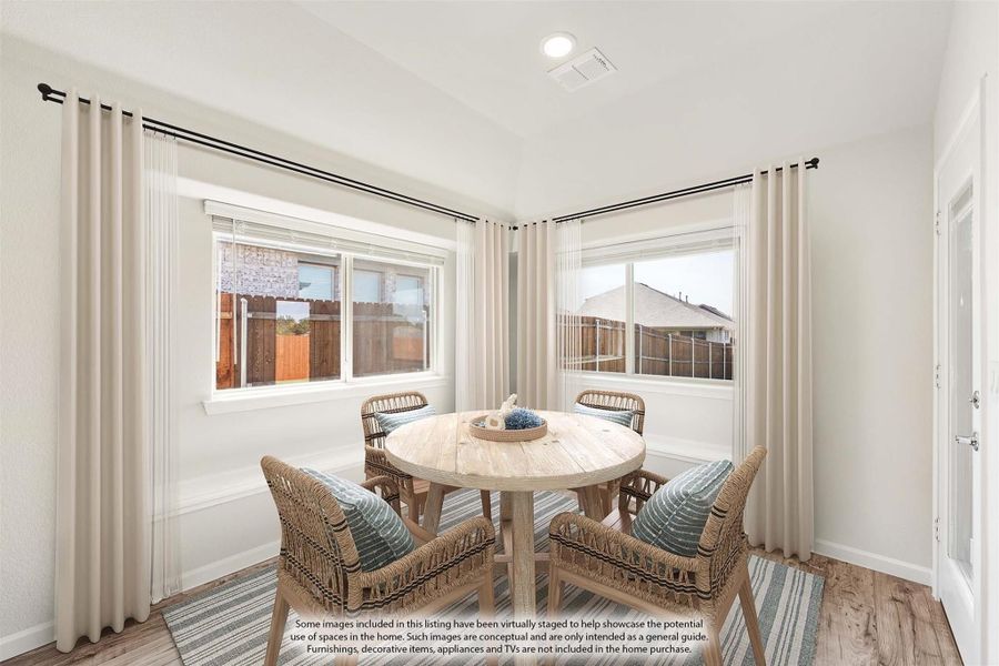 Bright breakfast nook with round wood table, four wicker chairs, and two large windows with curtains