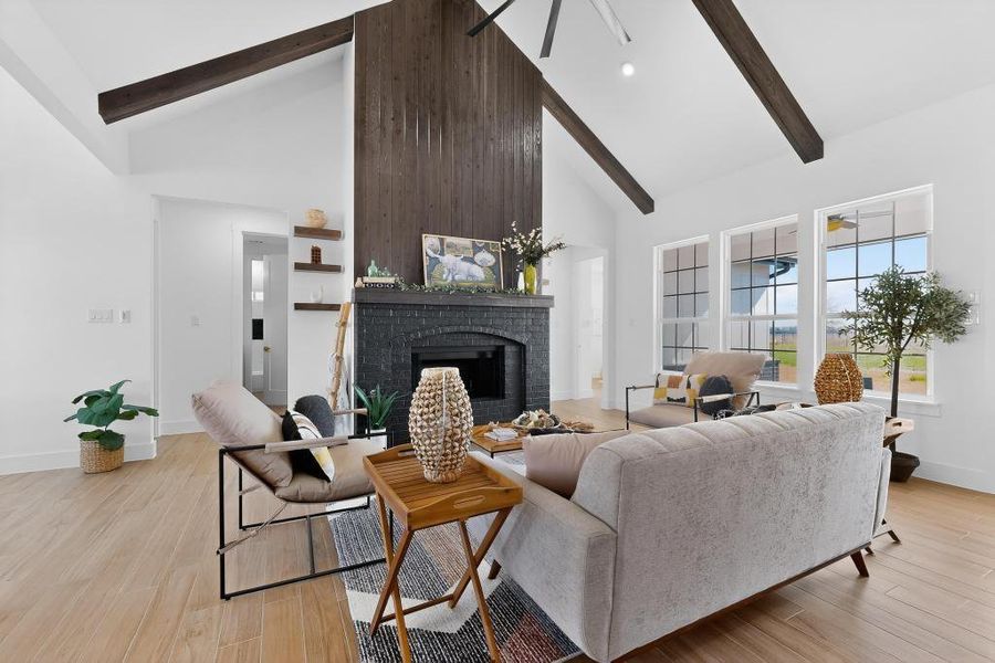 Living room with a fireplace, light wood finished floors, ceiling fan, and vaulted ceiling