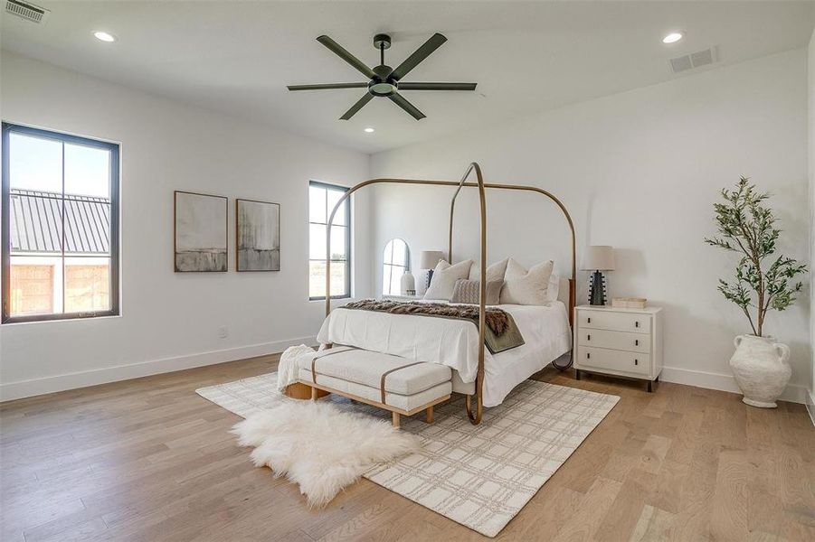 Bedroom with light hardwood / wood-style flooring, multiple windows, and ceiling fan