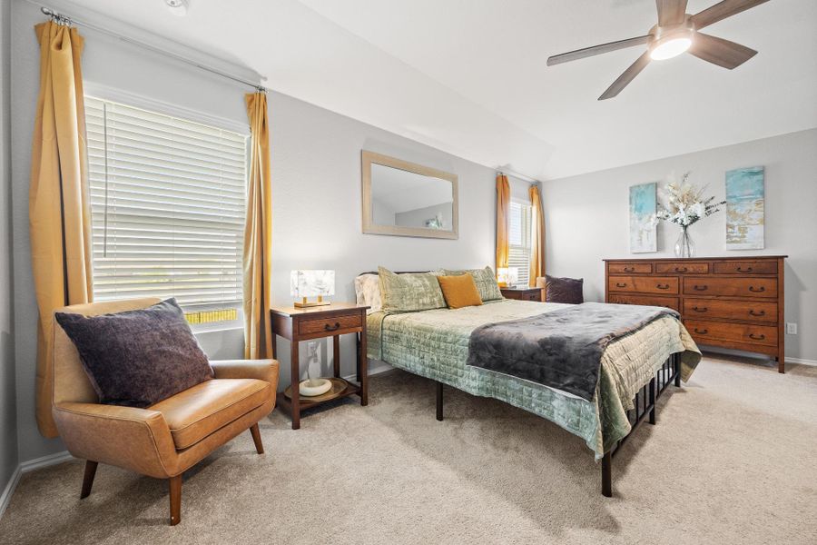 The primary bedroom features a vaulted ceiling, a ceiling fan, and ample natural light through well-lit windows. The primary bedroom features a vaulted ceiling, a ceiling fan, and ample natural light through well-lit windows.
